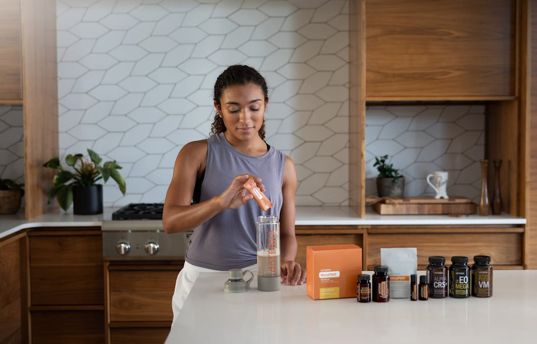 A woman preparing a drink in her kitchen with essential oils to hand