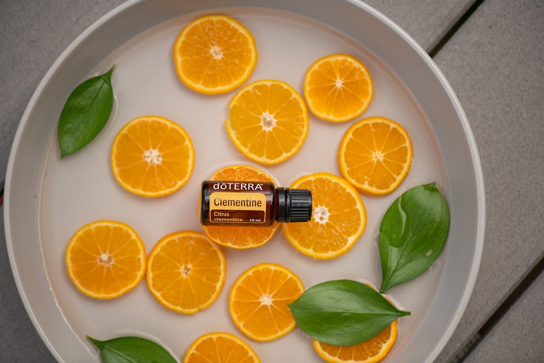 A bottle of citrus oil in a bowl of sliced oranges