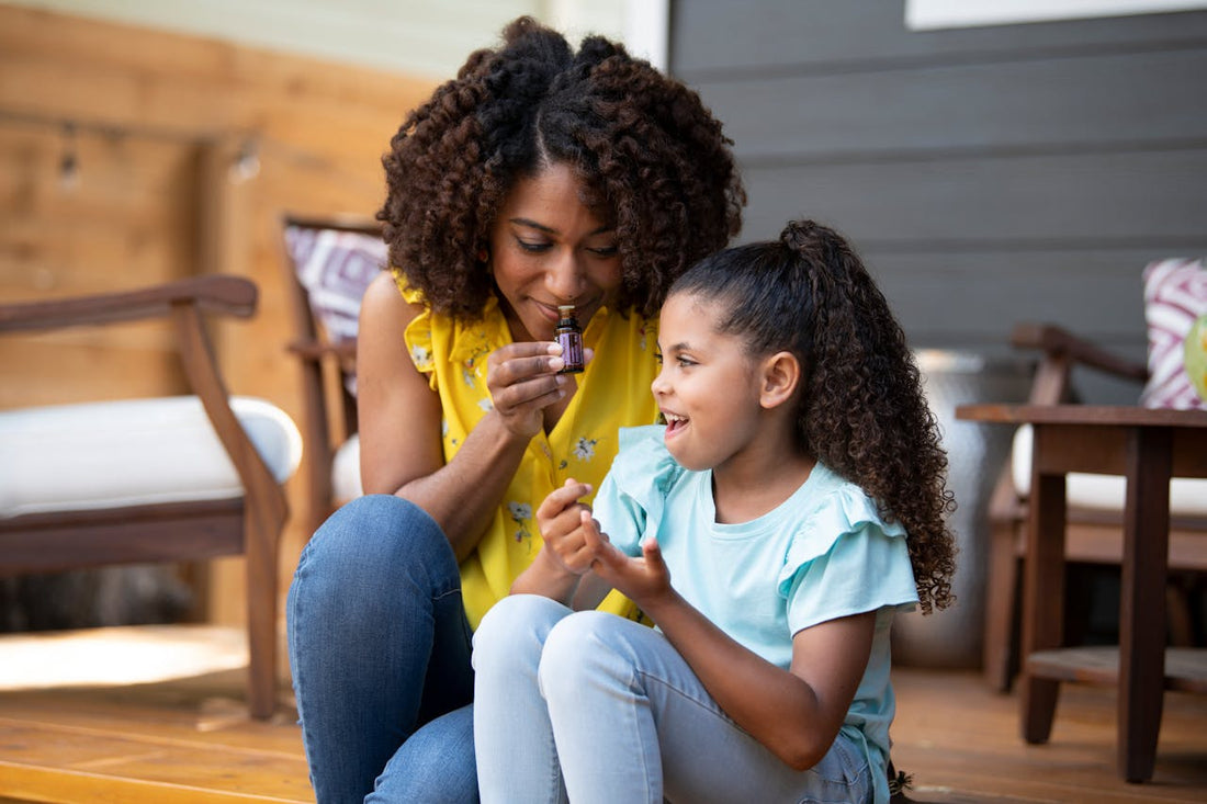 A parent and child applying a roll-on oil together