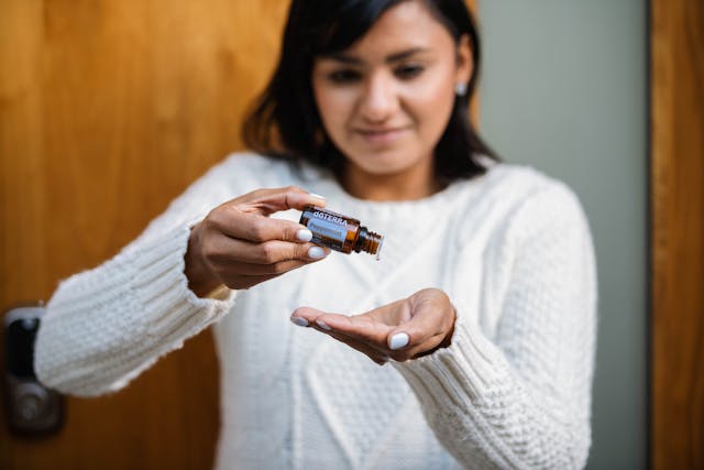A woman applying diluted essential oil to the back of her hand
